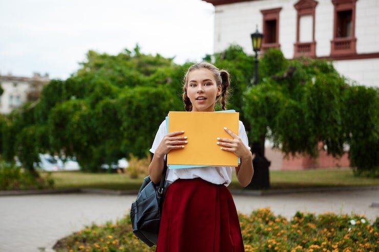 young-beautiful-cheerful-female-student-smiling-holding-folders-outdoors_176420-2415